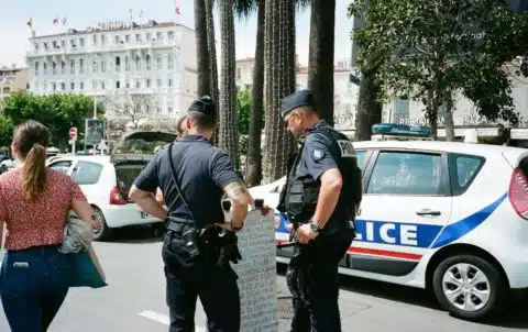 Two Police Men Standing Near Another Person Beside White and Blue Police Vehicle on Road