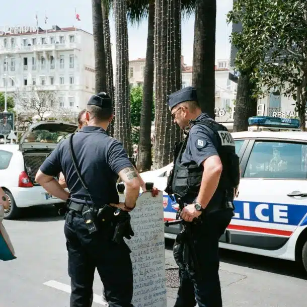 Two Police Men Standing Near Another Person Beside White and Blue Police Vehicle on Road